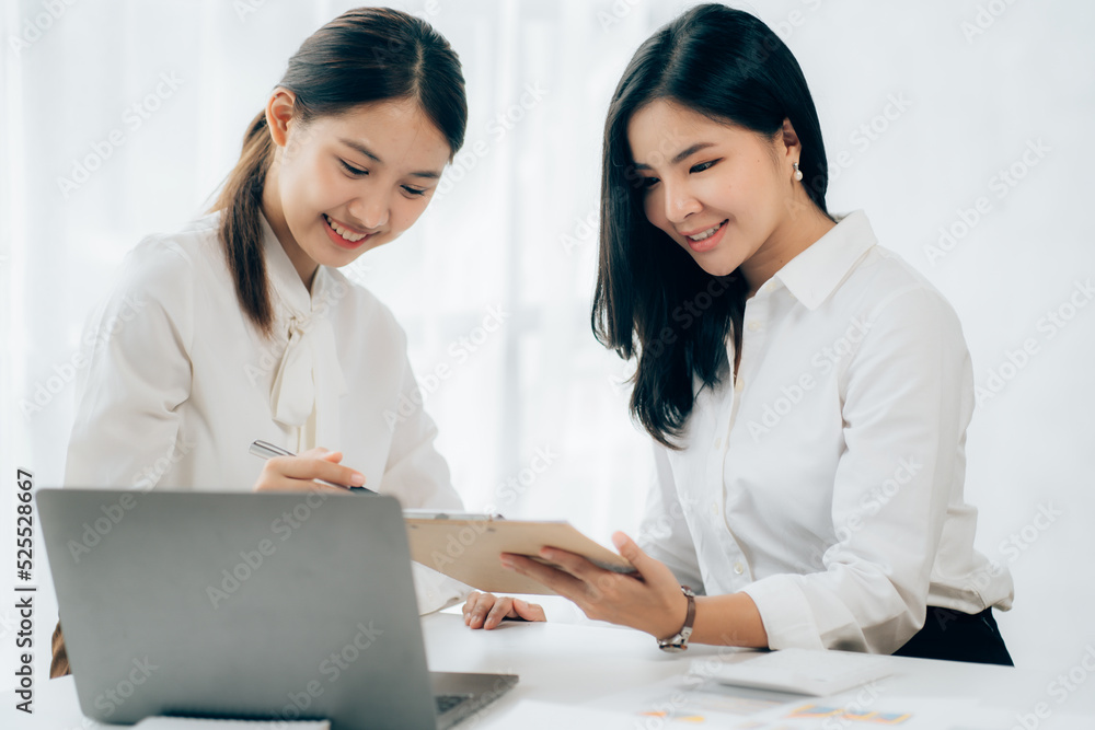 Two business Asian young women working together with laptop computer in the modern office.