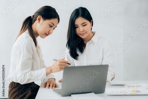 Two business Asian young women working together with laptop computer in the modern office.