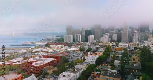 Flying over the gorgeous houses at the bay. Approaching the docks and blue waters of Pacific. San Francisco skyscrapers in the fog. photo