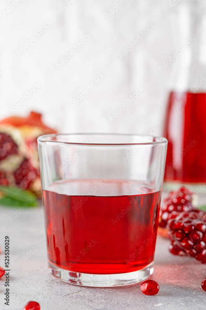 A glass of pomegranate juice with fresh pomegranate fruits on a gray concrete background. Vitamins and minerals. Healthy drink concept. Copy space. A glass of pomegranate juice with fresh pomegranate fruits on a gray concrete background. Vitamins and minerals. Healthy drink concept. Copy space.