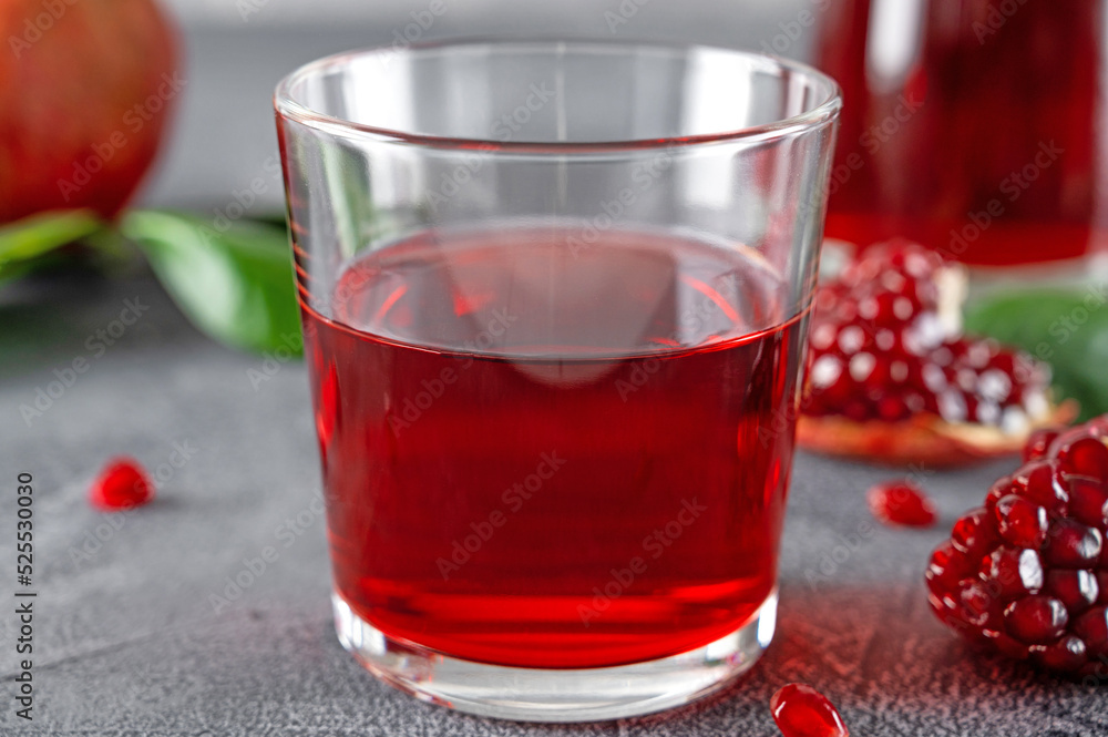 A glass of pomegranate juice with fresh pomegranate fruits on a gray concrete background. Vitamins and minerals. Healthy drink concept. Copy space. A glass of pomegranate juice with fresh pomegranate fruits on a gray concrete background. Vitamins and minerals. Healthy drink concept. Copy space.