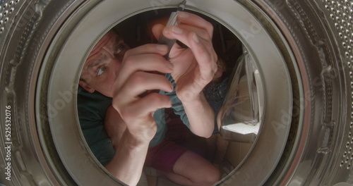 Dad's hands are repairing the washing machine. He twists the screwdriver in the drum, tightens the screws. He beats his hand on the drum. The girl turns the screwdriver.