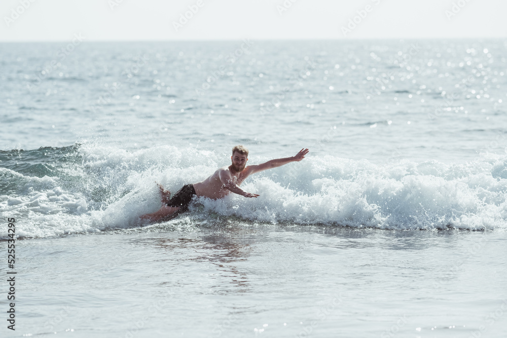 Young man doing a belly flop at beach