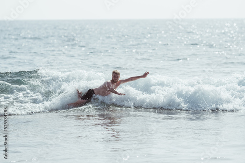 Young man doing a belly flop at beach photo