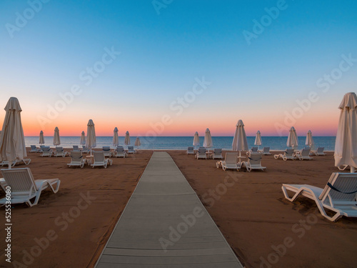 Umbrellas and sun loungers on the calm sea beach at sunrise photo