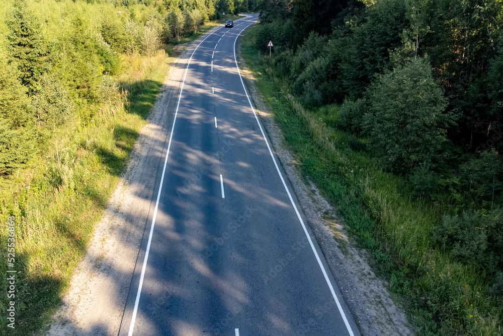 Fototapeta premium two-lane road in the forest in the summer on a sunny day