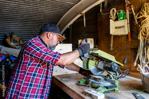 Focused male splitting wood with miter saw