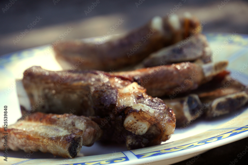 Close-up with defocused background of pork ribs cooked on a wood-fired grill