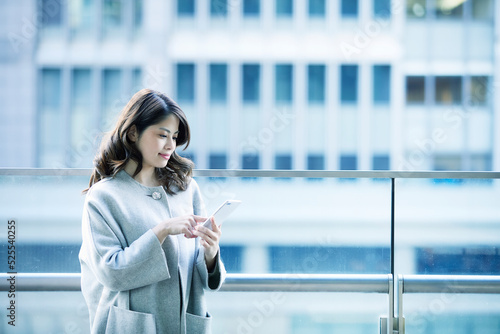 オフィス街でスマートフォンを持つ女性 photo