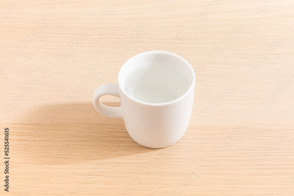 Cup of water isolated on wood background. Drinking water. White mug. Beverage. Wooden surface. Simplicity. Minimalist object.