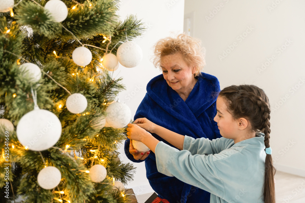 winter holidays and family concept - happy grandmother and baby granddaughter near christmas tree at home winter holidays and family concept - happy grandmother and baby granddaughter near christmas tree at home