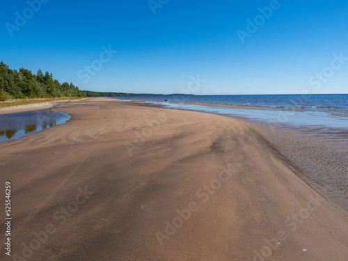 Clear water with small waves and sandy beach of Lake Ladoga in a sunny weather in the Republic of Karelia, Northwest Russia
