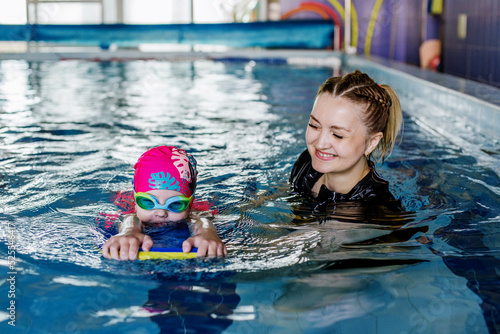 Kid learns to swim in pool. Swimming instructor teaches preschooler to swim in swimming pool