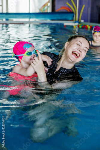 Kid learns to swim in pool. Swimming instructor teaches preschooler to swim in swimming pool