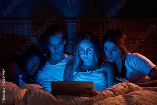Scared flatmates watching horrors in dark bedroom