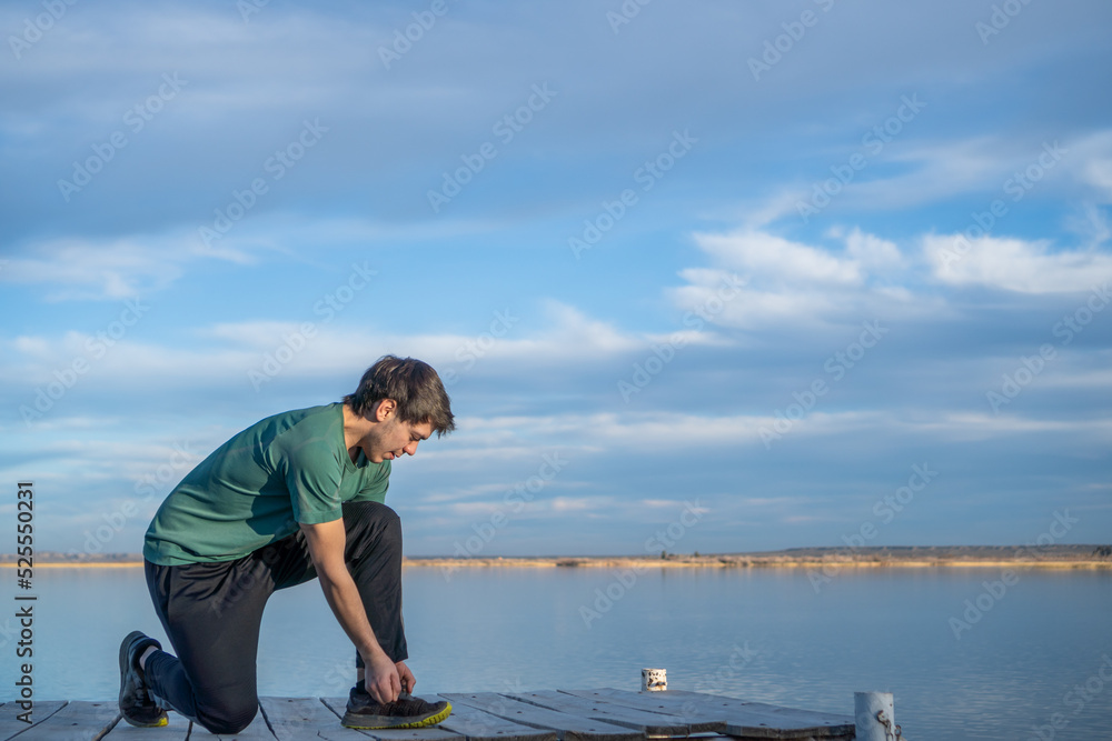 Naklejka premium young boy tying his shoelaces against a blue sky