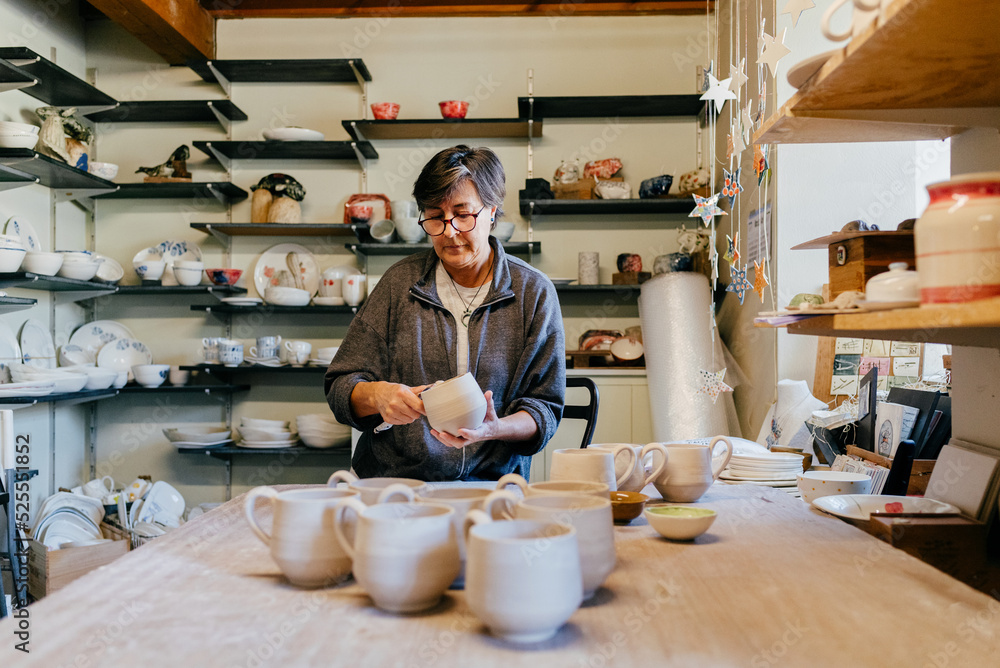 Craftswoman creating ceramic cups in workshop Craftswoman creating ceramic cups in workshop
