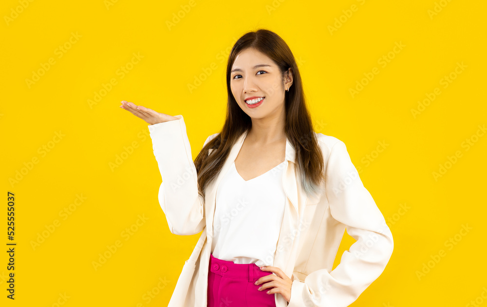 Young asian business woman long hair style posing hands presenting something on yellow color background. Young asian business woman long hair style posing hands presenting something on yellow color background.