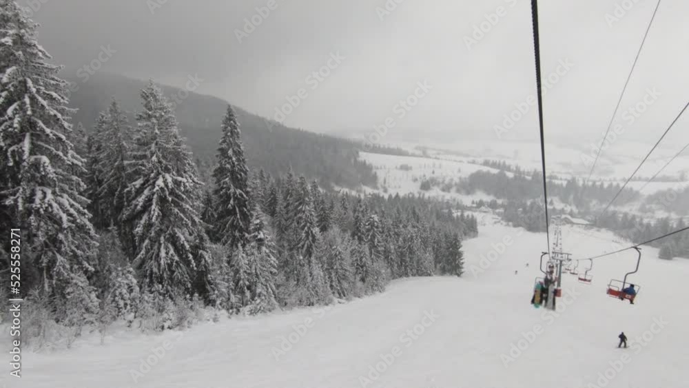 Ascending on a chair lift with trees covered in snow Ascending on a chair lift with trees covered in snow