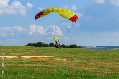 The parachutist successfully landed on the green grass. Air sports and entertainment.
