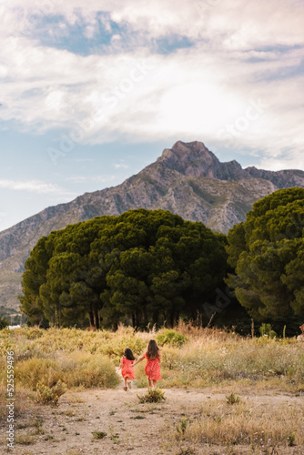 Girls in red dresses running in field photo