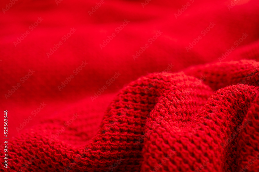 Knitted surface of woolen things as a background. Close-up of soft fabric red color knitted patterns texture. Warm winter clothing. Background textile surface with copy space for text.