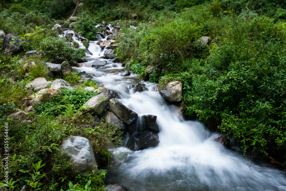 A wide angle shot of a river flowing through the forest with mountain surrounding in India. Dehradun city of uttarakhand.