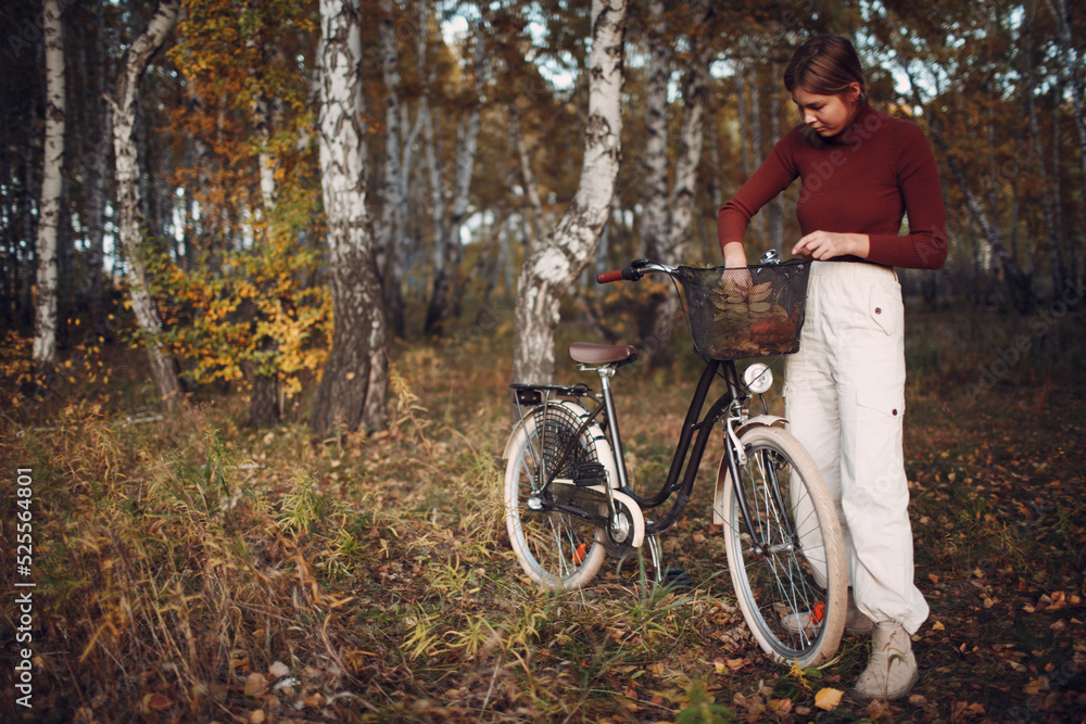 Happy active young woman riding bicycle in autumn park.
