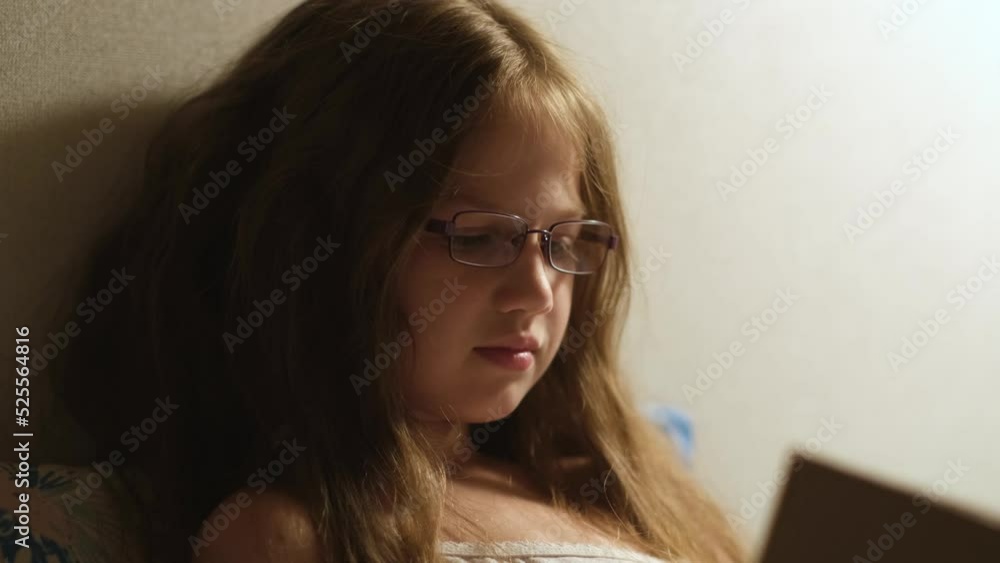 Child girl in glasses reading book in bed at night before going to sleep Child girl in glasses reading book in bed at night before going to sleep