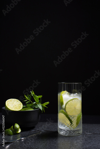 Un vaso de refrescante zumo de lima con rodajas de lima y hielo sobre fondo negro