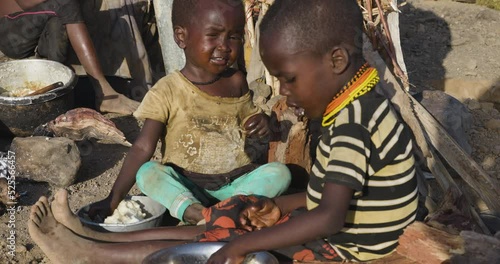 Close-up.Malnourished children due to extreme poverty, drought and climate change. Eating maize porridge infront of their dwelling.Kenya