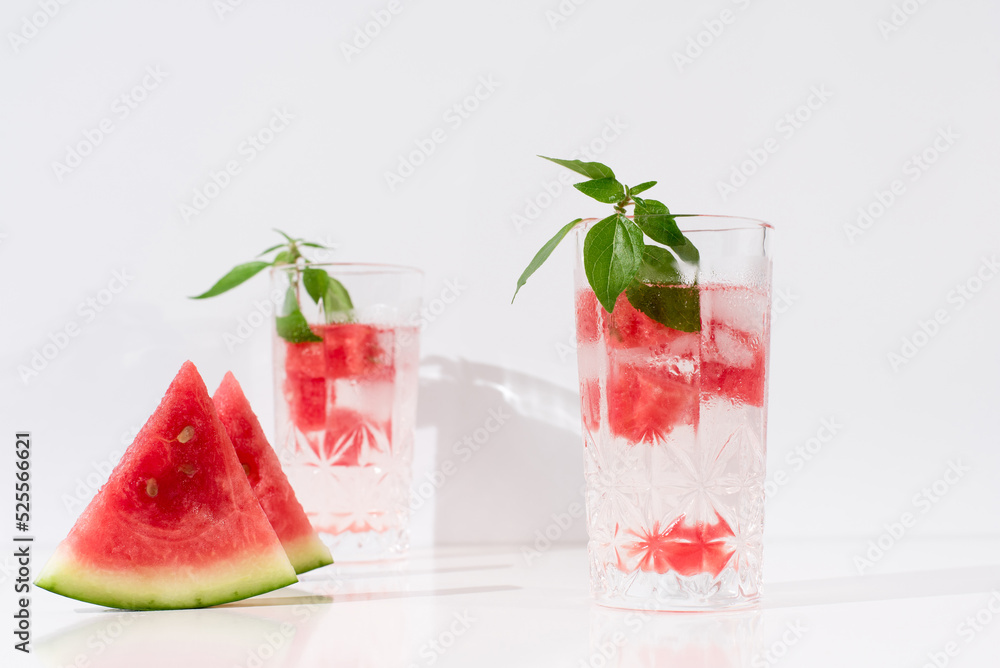 Dos vasos de zumo de sandía con trozos de sandia y hielo sobre fondo claro Dos vasos de zumo de sandía con trozos de sandia y hielo sobre fondo claro