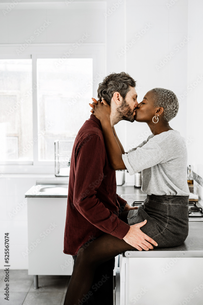 Multiethnic lovers cuddling and kissing in kitchen Multiethnic lovers cuddling and kissing in kitchen