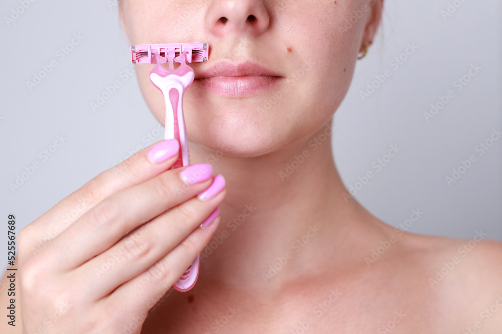 closeup of a woman shaving her face with a razor. face epilation