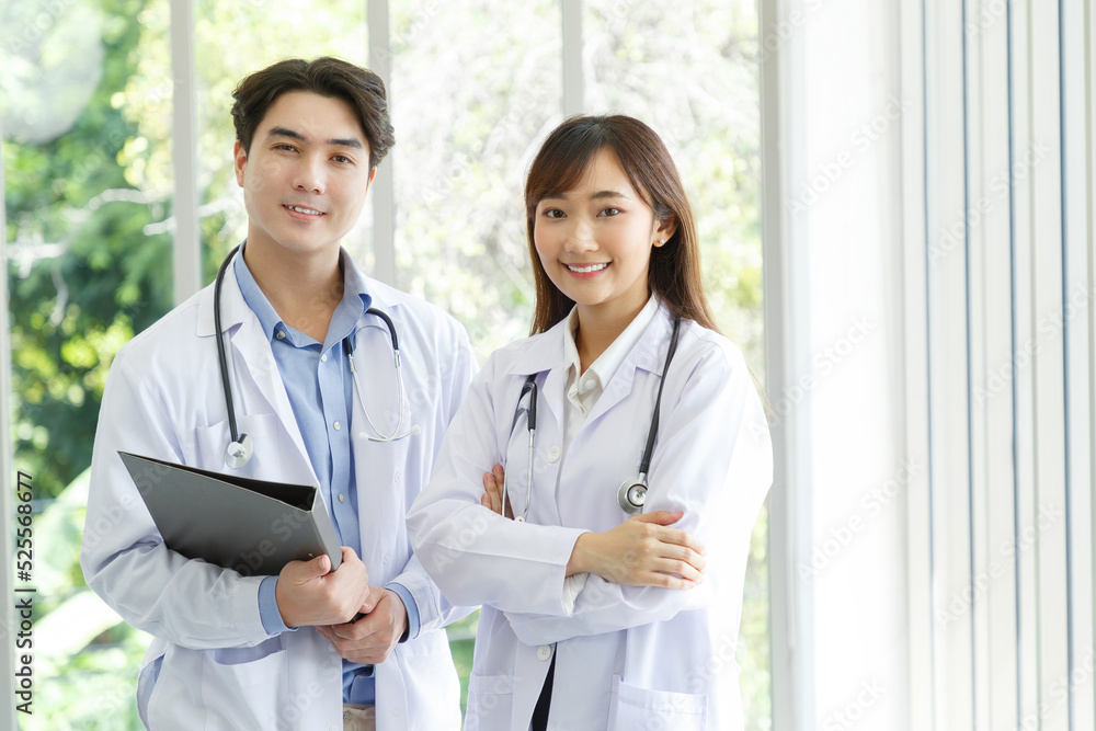 Medicine and healthcare concept : Happy and cheerful asian doctors, Male and Female holding files with stethoscope and smiling in lobby of hospital. Medicine and healthcare concept : Happy and cheerful asian doctors, Male and Female holding files with stethoscope and smiling in lobby of hospital.