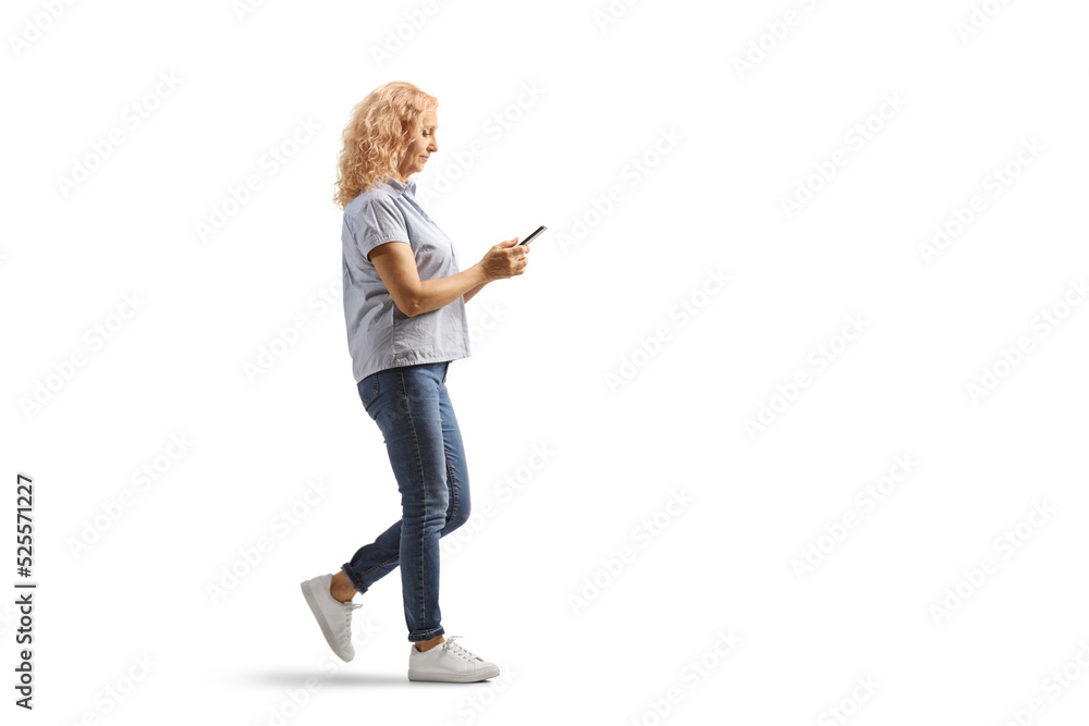 Full length profile shot of a casual mature woman walking and using a smartphone Full length profile shot of a casual mature woman walking and using a smartphone