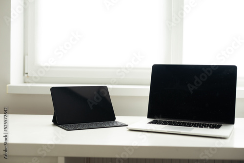 laptop and tablet on a white table.