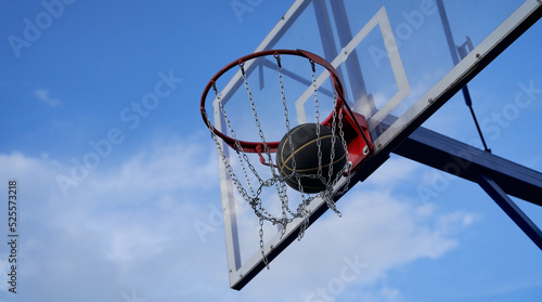 Street basketball ball falling into the hoop. Close up of black ball in the hoop net. © nuclear_lily