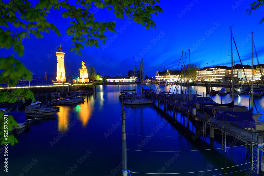 Der Hafen von Lindau am Bodensee zur Blauen Stunde mit beleuchteten Häusern und dem Illuminierten Wahrzeichen, dem Leuchtturm.