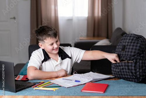 Caucasian kid smiling and taking something from his schoolbag