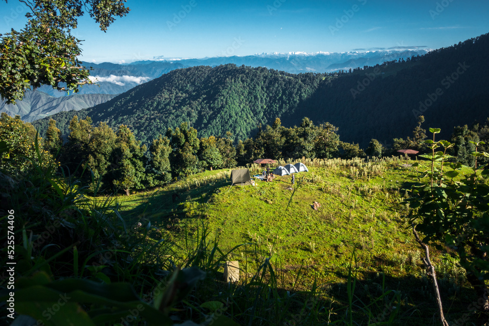 A wide angle shot of Camping in the hills of Himalayan region of Uttarakhand, India with visible Gomukh Glacier peaks in the background.