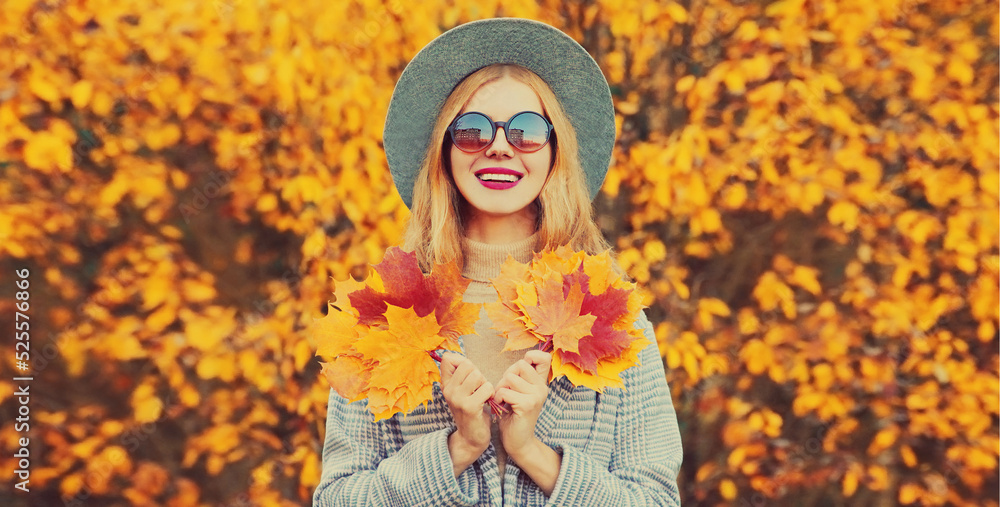 Autumn portrait of beautiful happy smiling woman with yellow maple leaves wearing round hat in the park Autumn portrait of beautiful happy smiling woman with yellow maple leaves wearing round hat in the park