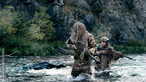 Two mercenary soldiers crossing the river after the completion of the sabotage operation. Soldiers covertly leave the combat area, fording across the river. photo