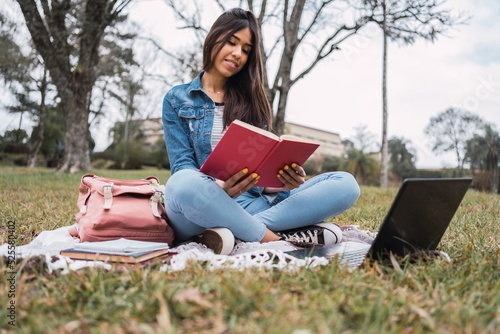 Student with book and laptop in park photo