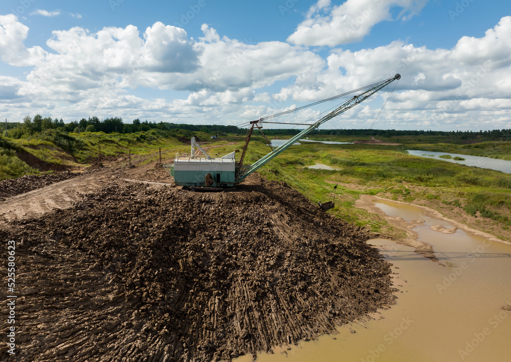 Dragline excavator works in an open pit for the extraction of clay