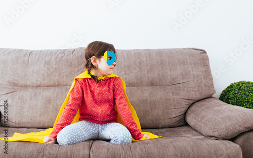 Girl in mask and cape pretending to be superhero
