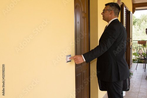 Photo Image of a stylish tax collector with briefcase ringing a house bell insistently