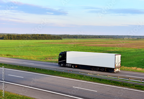 Truck with semi-trailer driving on highway on sunset. Goods delivery by roads. Services and Transport logistics. Lorry Transport in motion. Long Self-driving lorries. Semi-trailer truck on freeway..