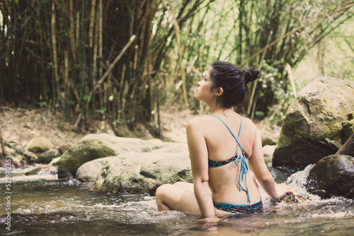 Girl on vacation in a spa. Girl bathing in a river. Woman with hat. River with stones and bamboo