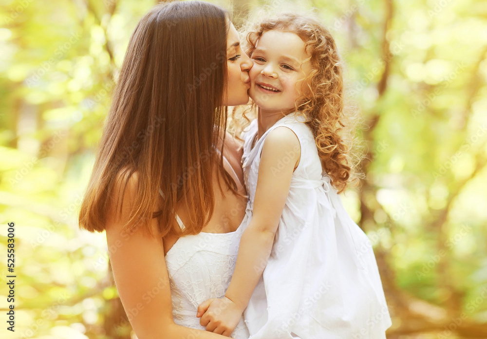 Mother kissing her little daughter child in summer park Mother kissing her little daughter child in summer park